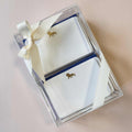 An elegant navy blue stationery box with gold accents, containing assorted paper, envelopes, and writing tools.