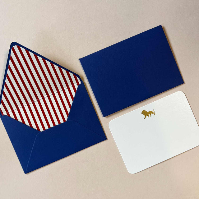 An elegant navy blue stationery box with gold accents, containing assorted paper, envelopes, and writing tools.